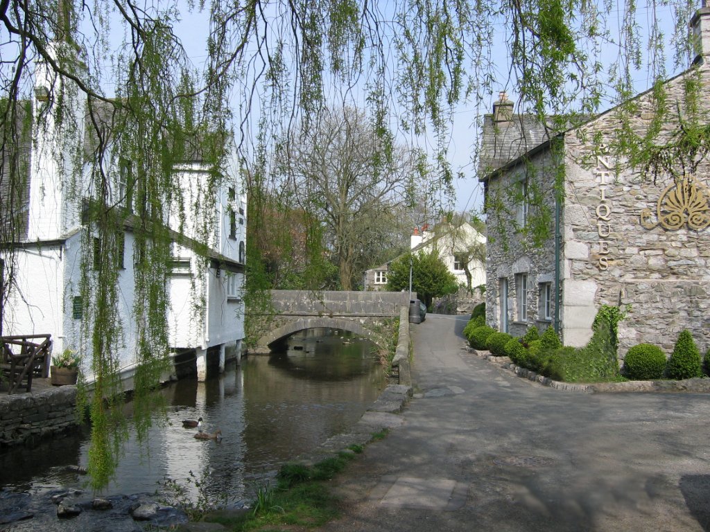 Cumbria's Hidden Village Escapes: A Stone bridge over a calm waterway in Cartmell Village with white and stone buildings nearby. Cumbria's Hidden Village Escapes: A Stone bridge over a calm waterway in Cartmell Village with white and stone buildings nearby.